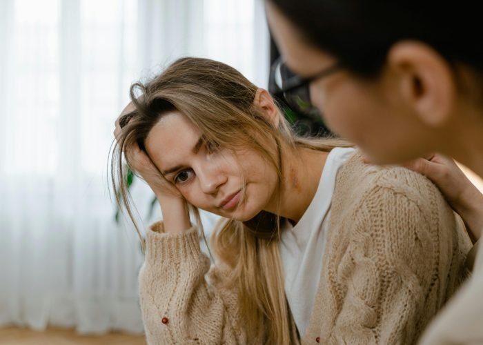 Woman receiving comforting support, showing empathy and understanding in a thoughtful indoors setting.